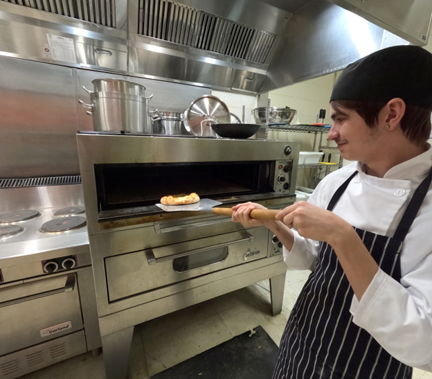Prepared pizza goes in to the oven. Open Gallery